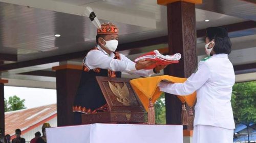 Caption: Bupati Mahulu saat menyerahkan bendera merah putih yang dikibarkan paskibrakan dari putra putri terpilih siswa SMA Long Bagun, Selasa (17/8/2021)